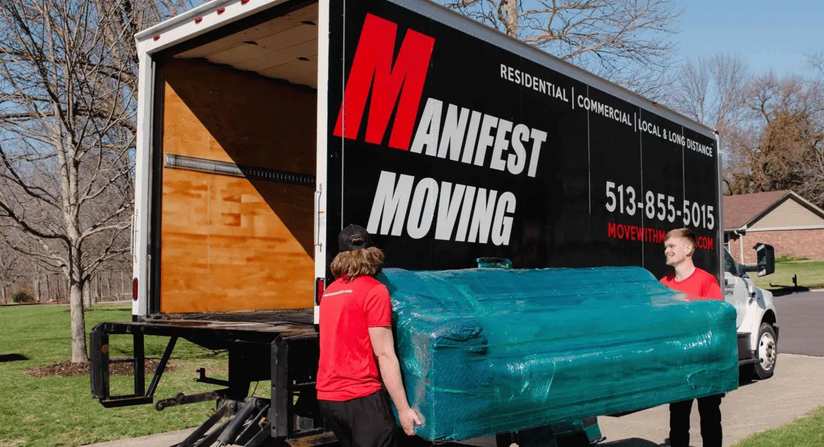 Manifest Moving crew loading a wrapped sofa into a moving truck